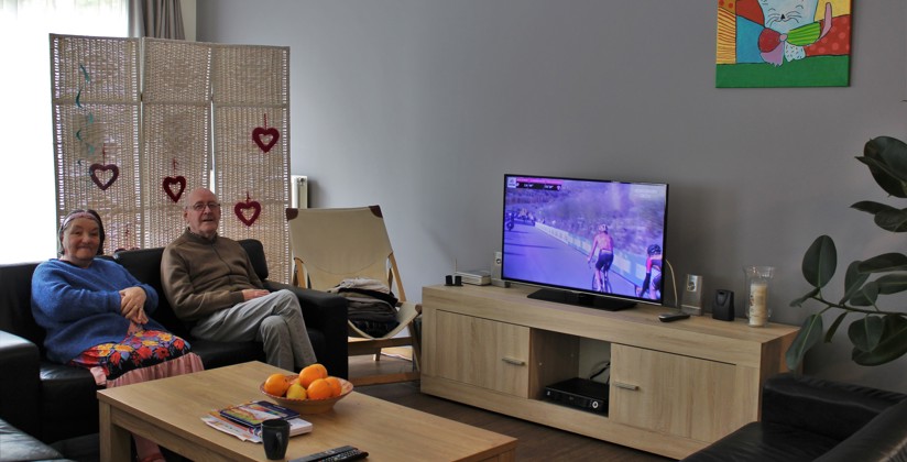 Man en vrouw zitten in de zetel in hun studio in een woonhuis