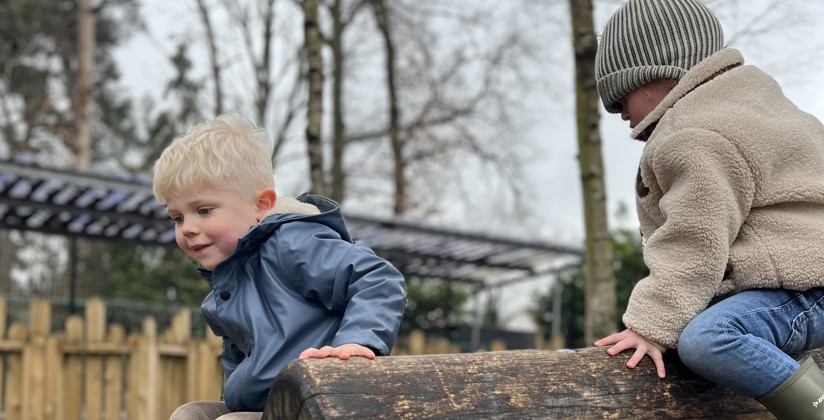 twee jongens spelen op houten balken