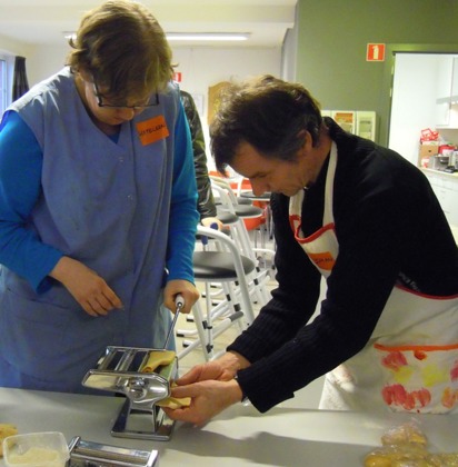 Man helpt vrouw bij het maken van pasta 