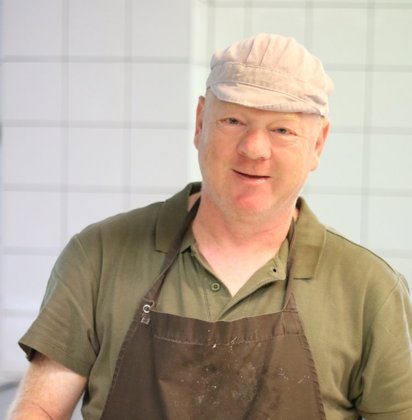 Man aan het werk in de keuken glimlacht naar de camera