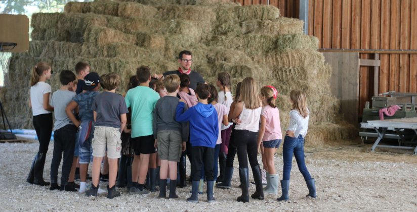 Groep kinderen krijgen uitleg van de boer van zorgboerderij Meander