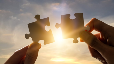 Artikelfoto: twee handen die elk een puzzelstuk vasthouden
