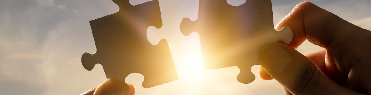 twee handen die elk een puzzelstuk vasthouden