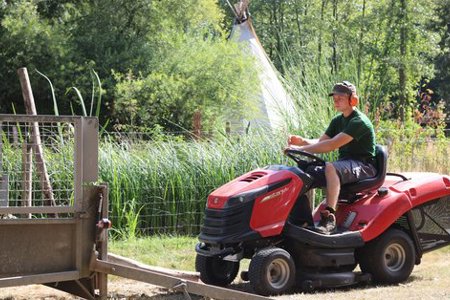 Een jonge man rijdt met een grasmachine