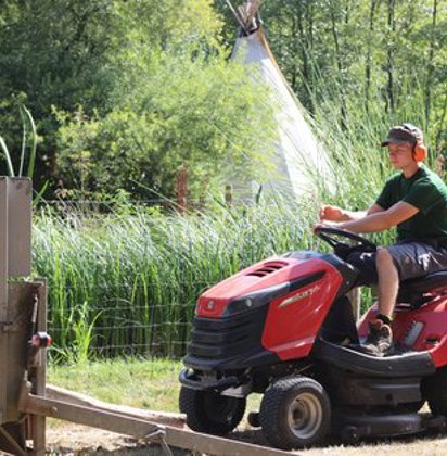 Een jonge man rijdt met een grasmachine