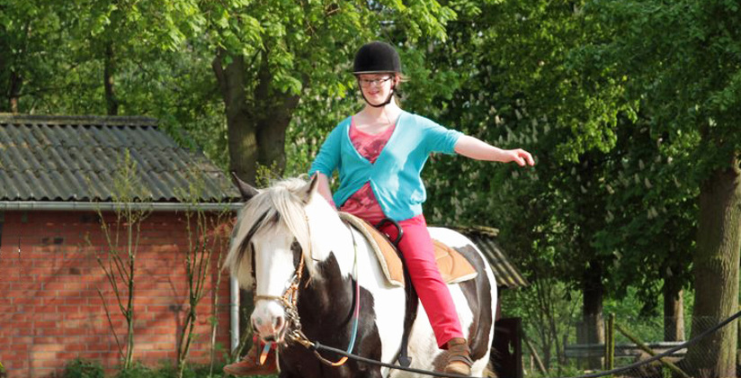 Paard aan de lounge met een vrouwelijke ruiter die een arm uitsteekt