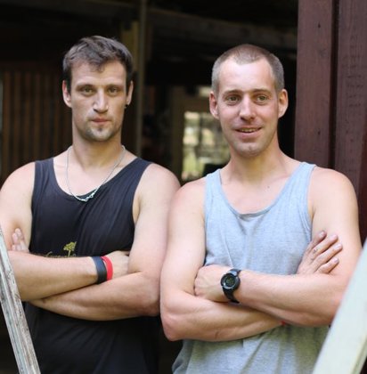 Twee mannen met gekruiste armen poseren voor de camera