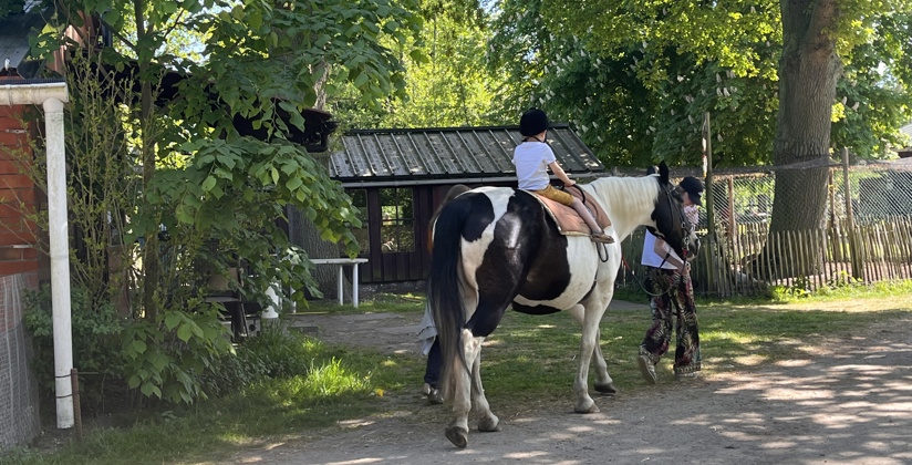 Jong kindje op een paard dat wordt vastgehouden door een begeleider