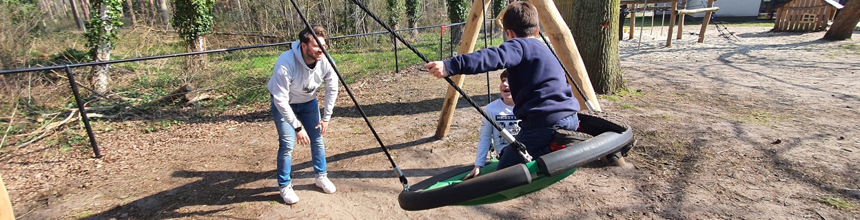 Begeleider Jaimy speelt met kinderen op een schommel 