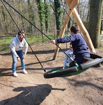 Begeleider Jaimy speelt met kinderen op een schommel 