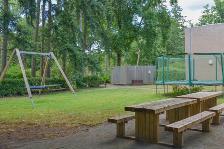 Tuin van een leefgroep van het mulitfunctioneel centrum met schommel, banken en trampoline 