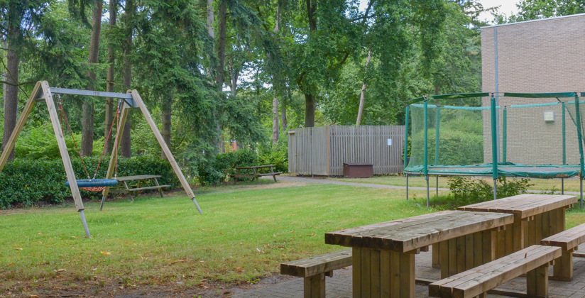 Tuin van een leefgroep van het mulitfunctioneel centrum met schommel, banken en trampoline